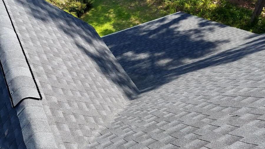 Finished asphalt shingle roof with a valley where two slopes meet and a ridge line along the left edge