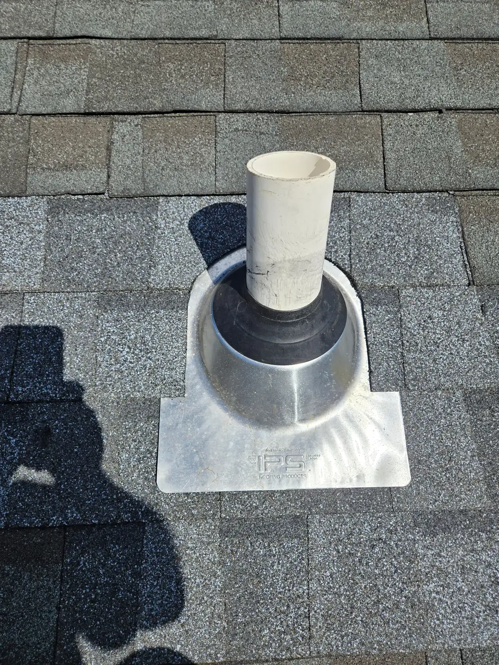 New flashing installed around a roof vent pipe with shingles in place