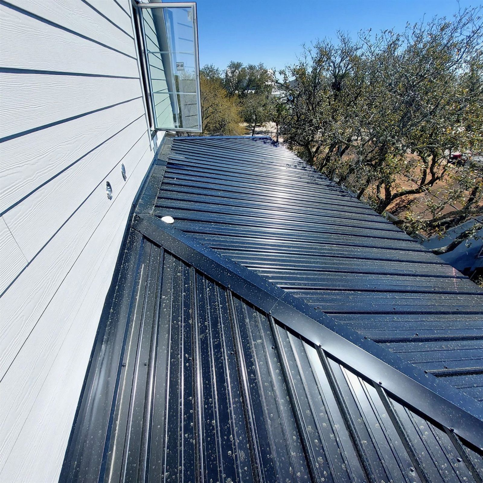 Dark metal roof eave detail beside a wall