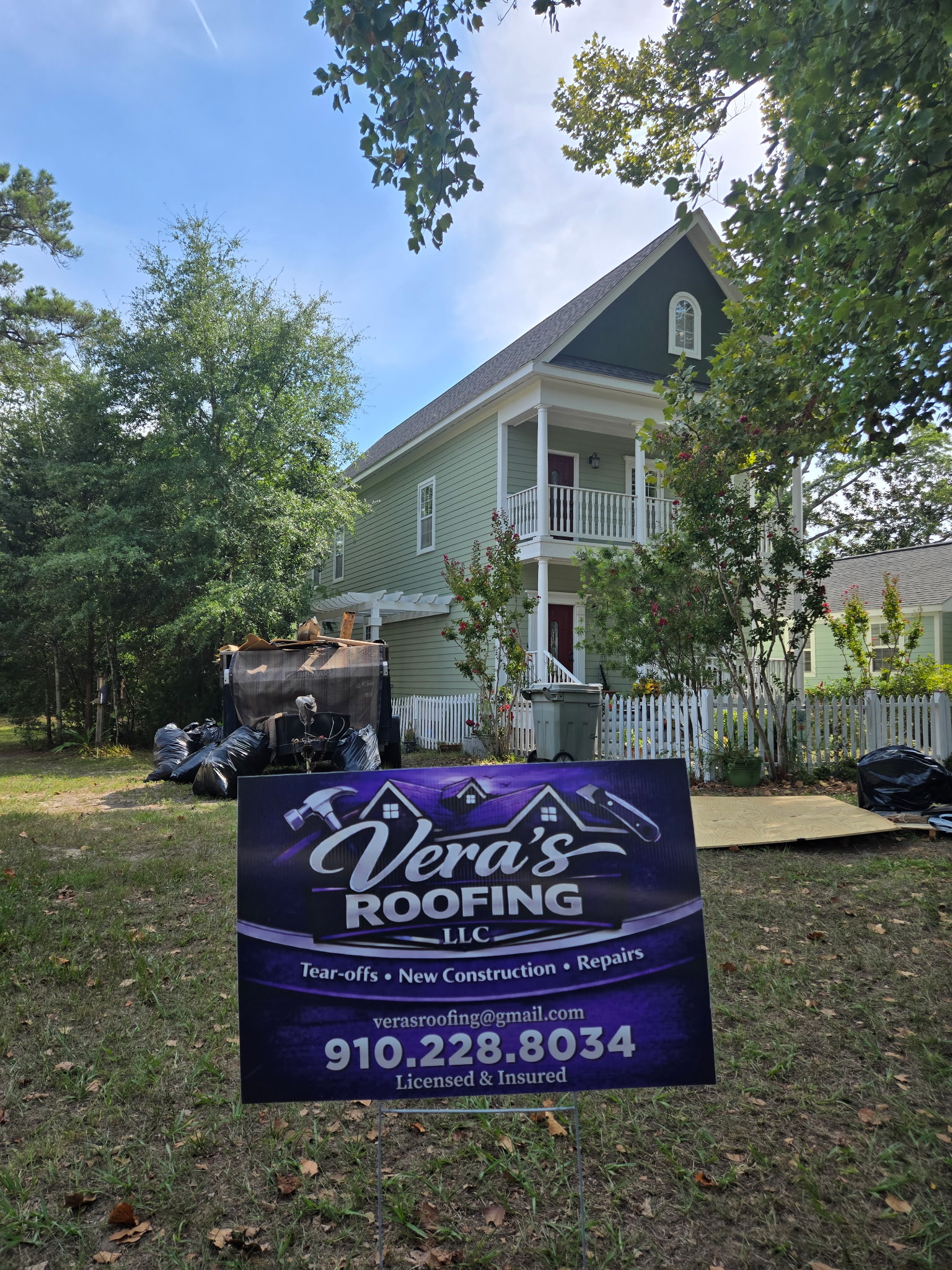 Green house at a Vera's Roofing jobsite in Southport, with the company sign in the foreground